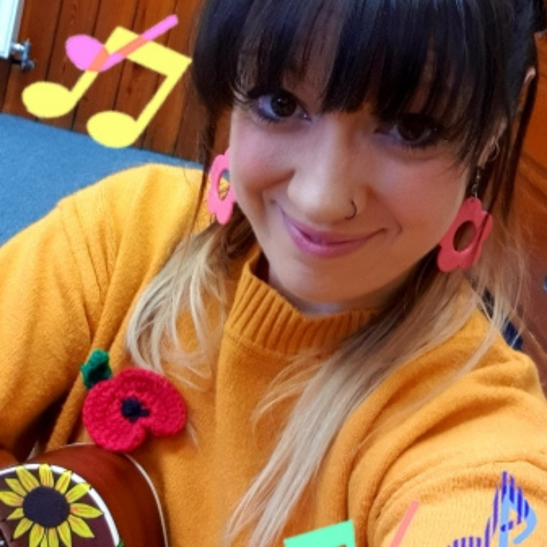 A photo of Abi. She has dark hair and is wearing a bright yellow jumper.